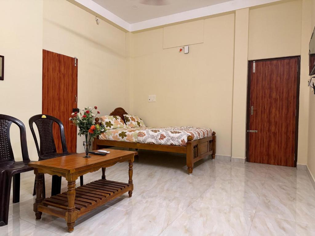a bedroom with a bed and a table with flowers on it at Serinity Saral in Pondicherry