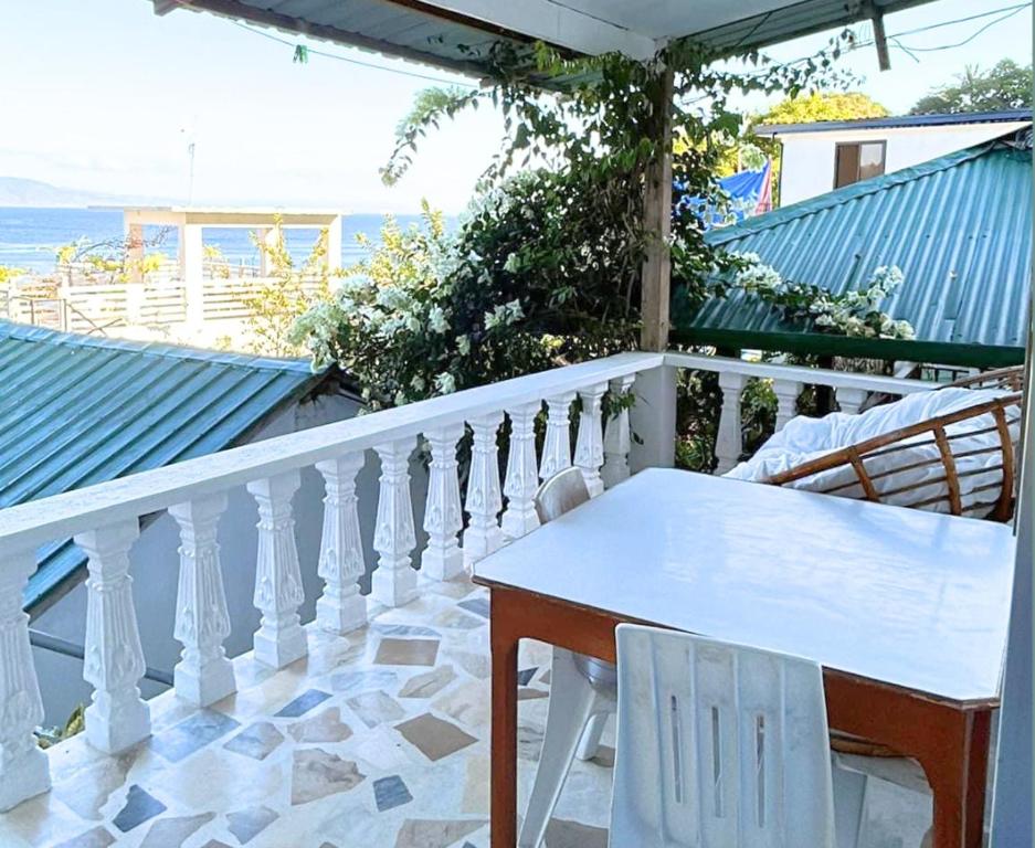 a white table and chairs on a balcony with the ocean at Villa Sabang in Puerto Galera