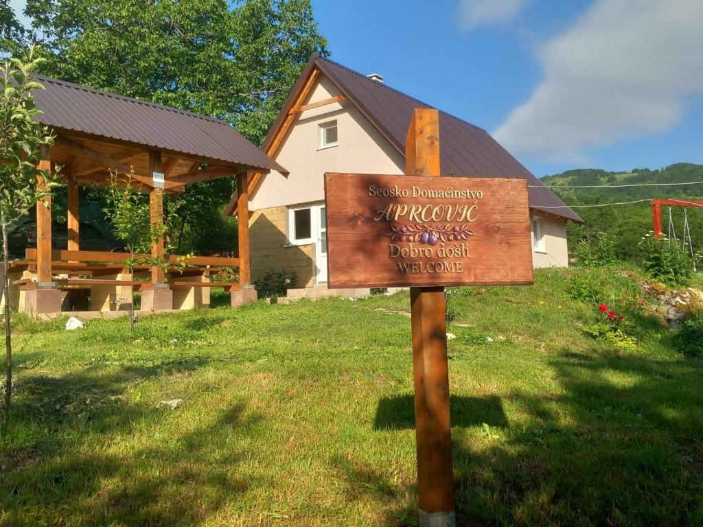 a sign in the grass in front of a house at Seosko domaćinstvo Aprcović in Plužine