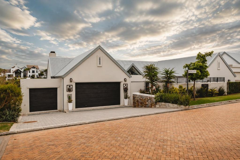 a white house with two garage doors on a driveway at Moorlands Manor in George