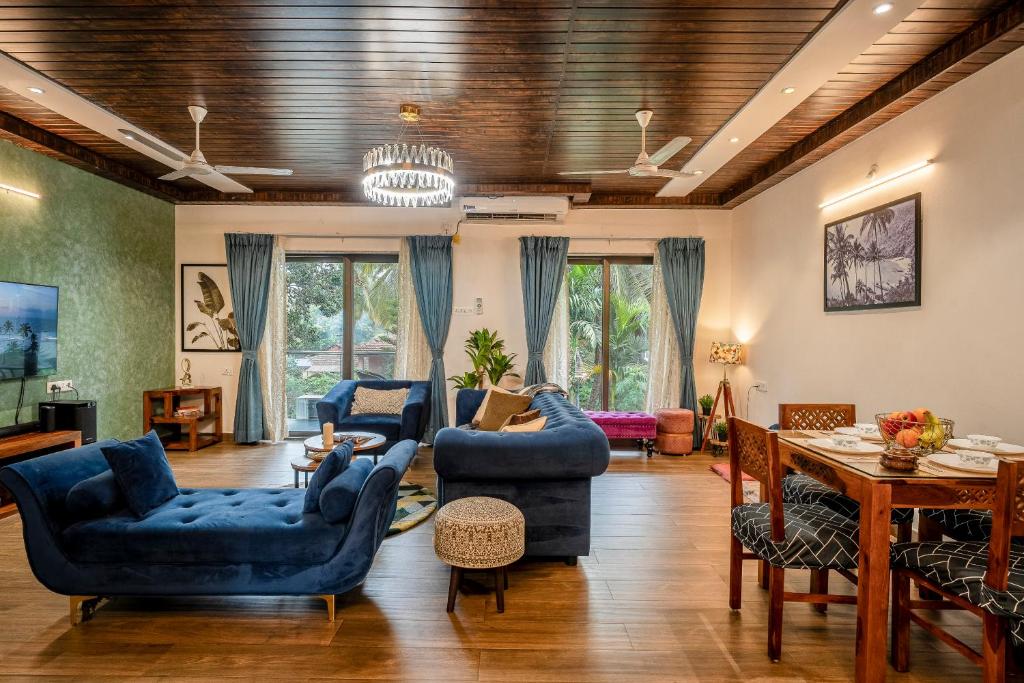 a living room with blue chairs and a table at Go Offline Homes - Designer 2BHK with Pool Near Candolim in Parra