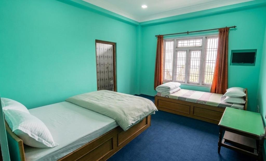 ein blaues Schlafzimmer mit zwei Betten und einem Fenster in der Unterkunft Hotel Nigale in Dhankuta