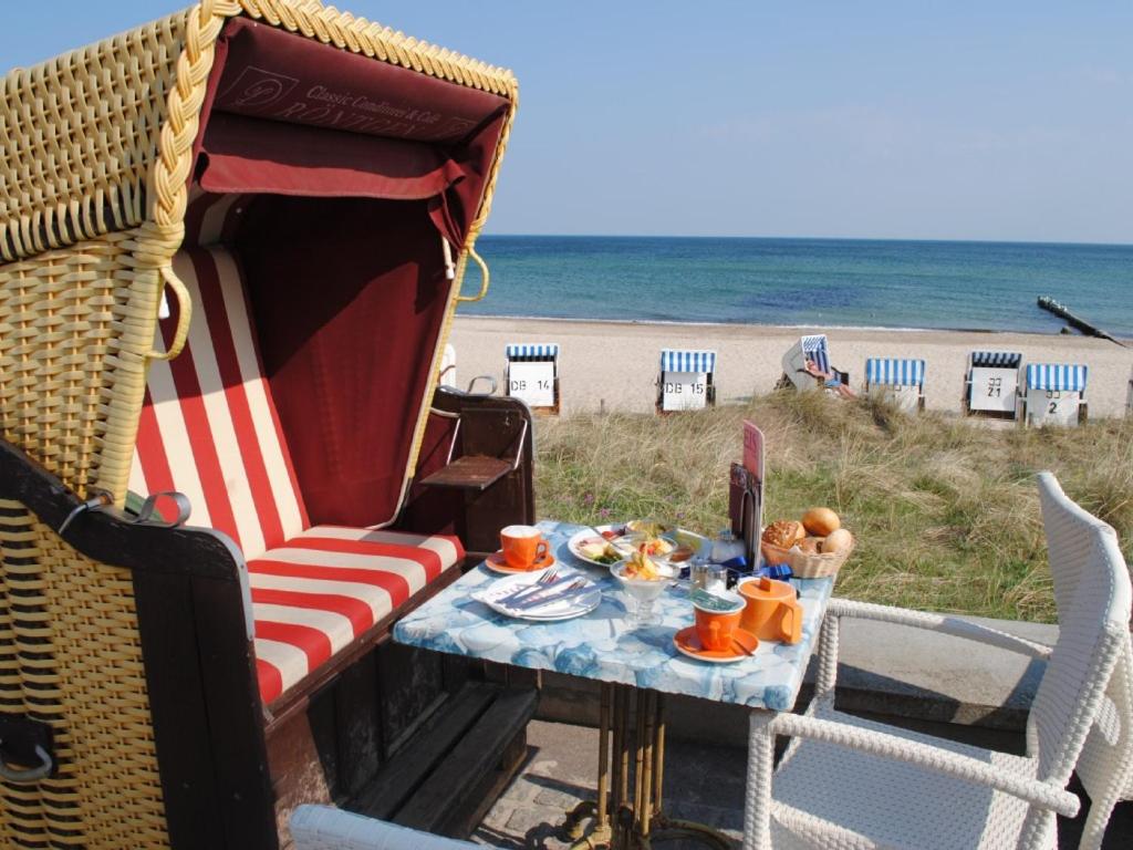 einen Tisch mit einem Stuhl und einem Tisch mit Essen am Strand in der Unterkunft Fewo Schwalbennest am Meer-exklusiv-eigener Strandzugang in Kühlungsborn