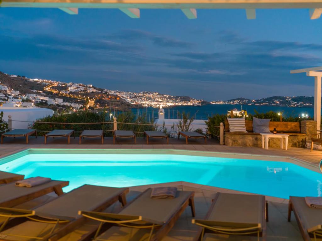 a swimming pool with chairs and a view of the ocean at Rhenia Mykonos Hotel & Bungalows in Tourlos