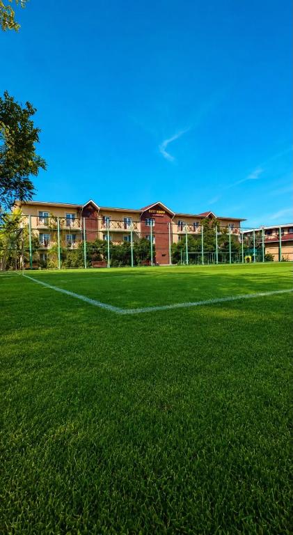 a large field of grass in front of a building at Dostar Beach Hotel - Достар Жағажай Қонақүйі in Aktau
