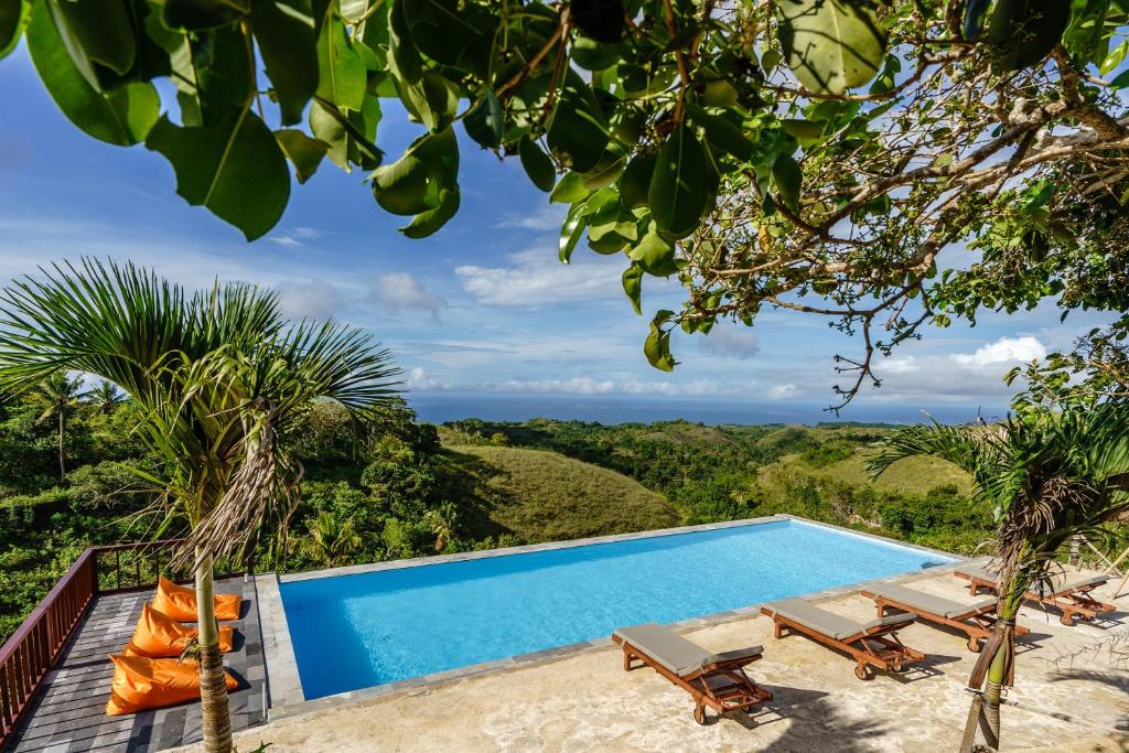 a pool with chairs and a view of the ocean at Pini Sentana Village Nusa Penida in Nusa Penida
