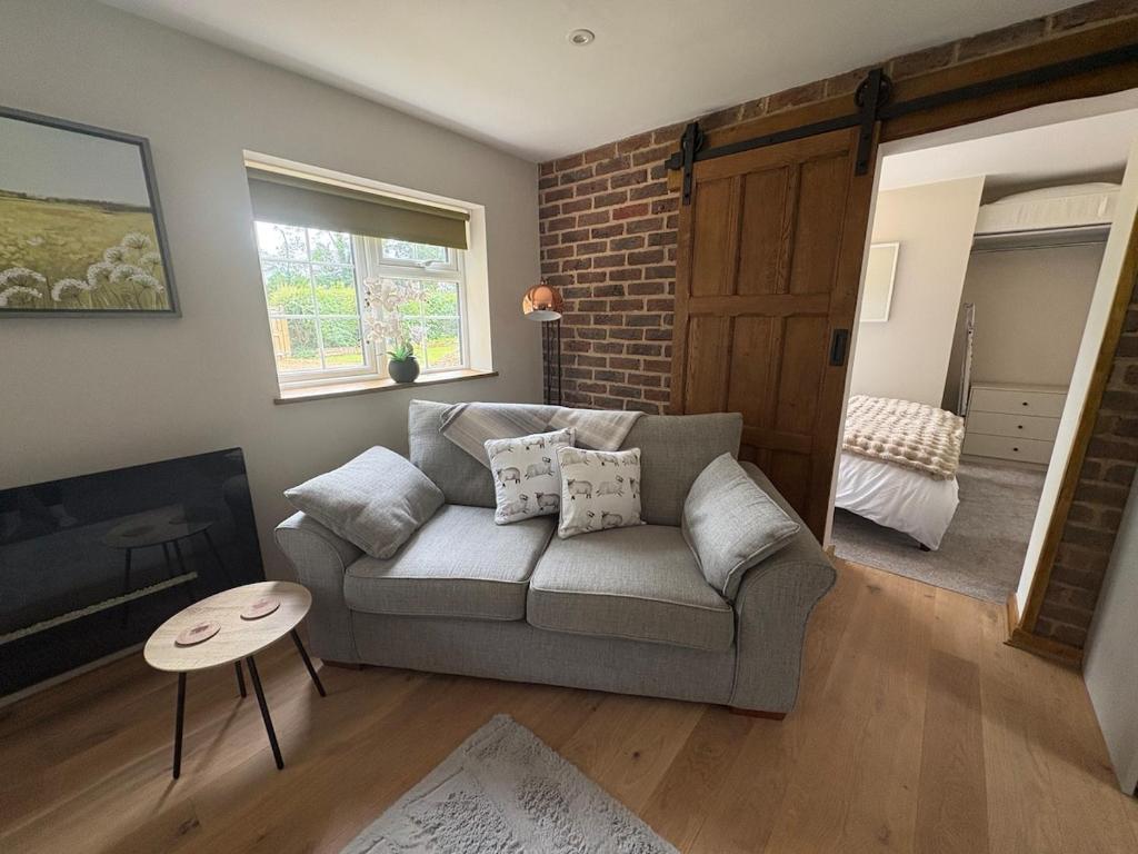 a living room with a couch and a brick wall at Gatwick 'Bit on the Side' in Copthorne