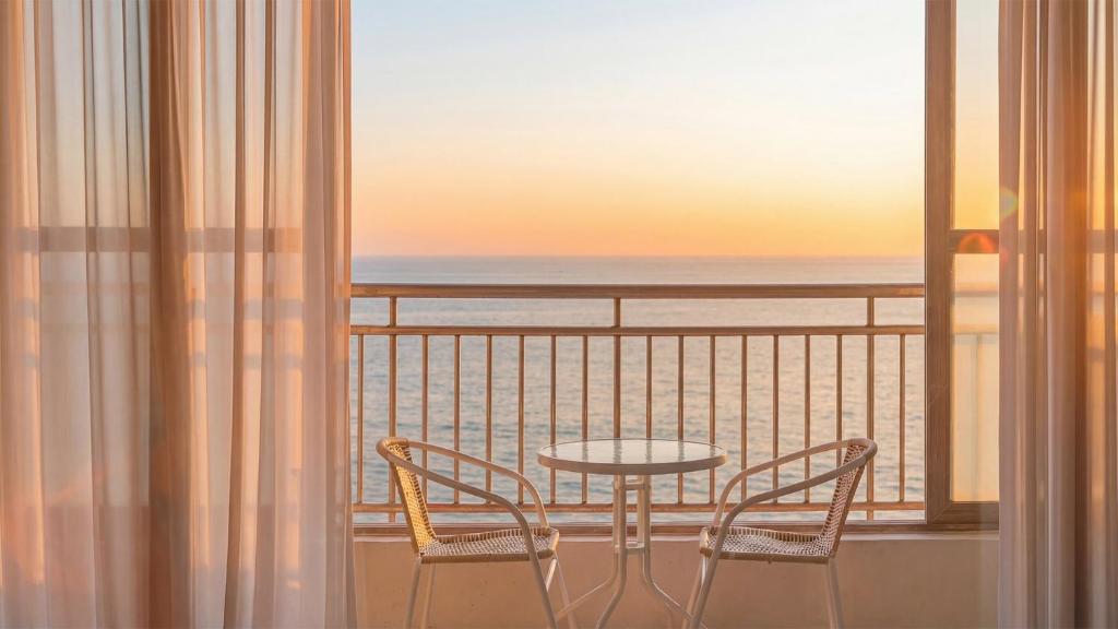 a table and chairs on a balcony with a view of the ocean at Pohang Baritdol Pension in Pohang