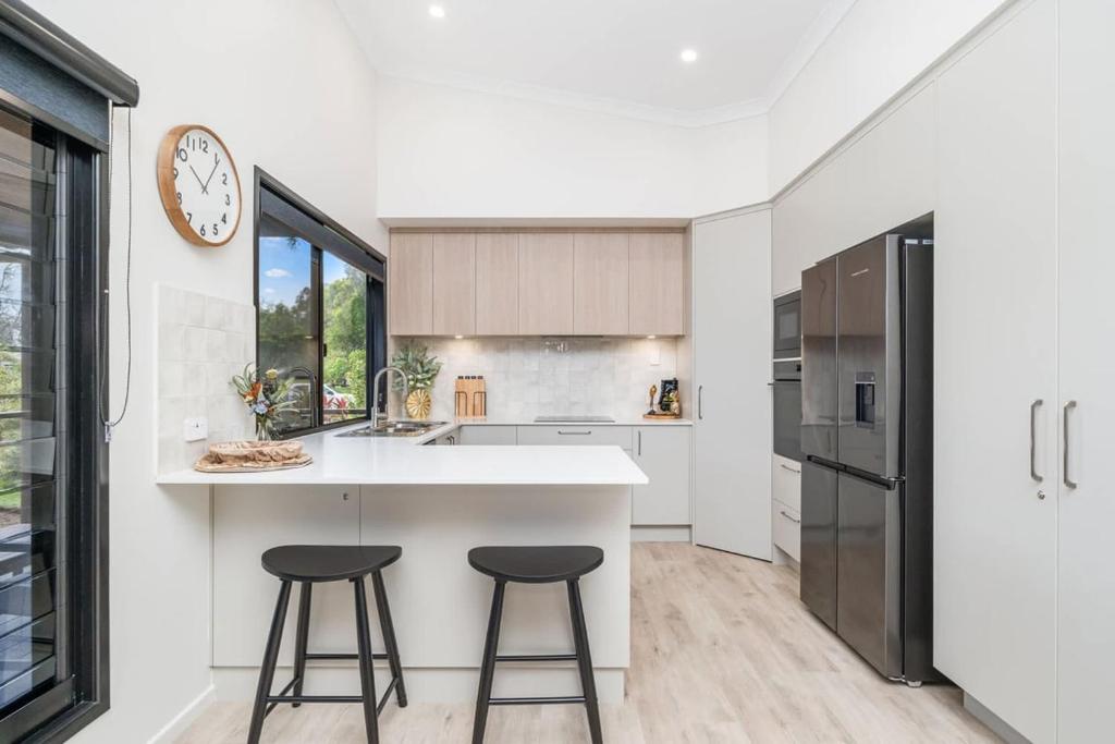 a kitchen with two bar stools and a counter top at The Luxe Breeze Bungalow in Hervey Bay