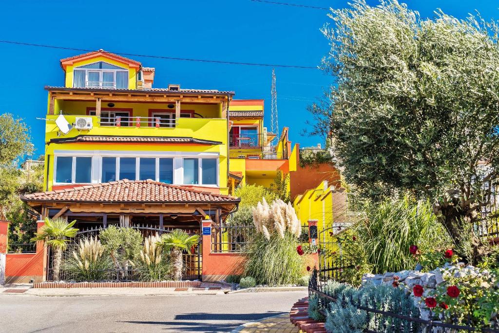a yellow and orange house with trees and plants at Apartments Maslina in Crikvenica