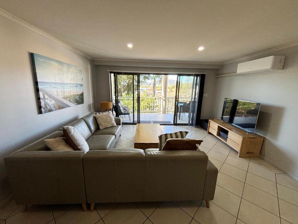 a living room with a couch and a flat screen tv at Jubilee Apartment 11 - Bring your own linen in South West Rocks
