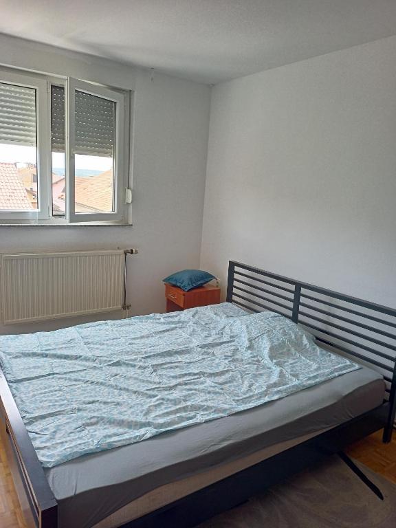 a bedroom with a bed with a blue blanket on it at njegoševa in Derventa