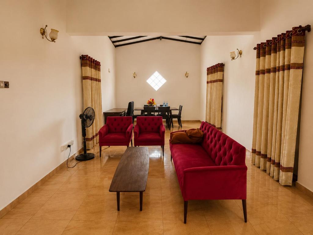 a living room with two red couches and a table at Sattvic Ceylon- Wellness Homestay in Colombo