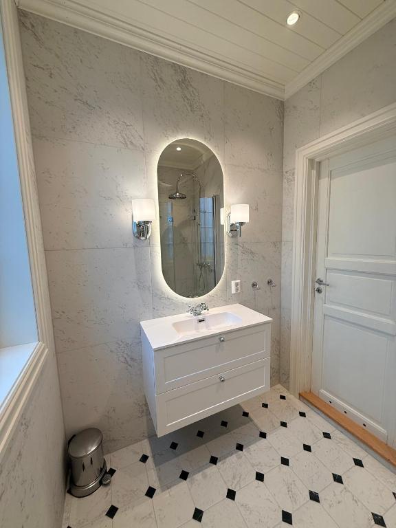 a white bathroom with a sink and a mirror at Nyoppusset leilighet i klassisk hus! in Lillehammer