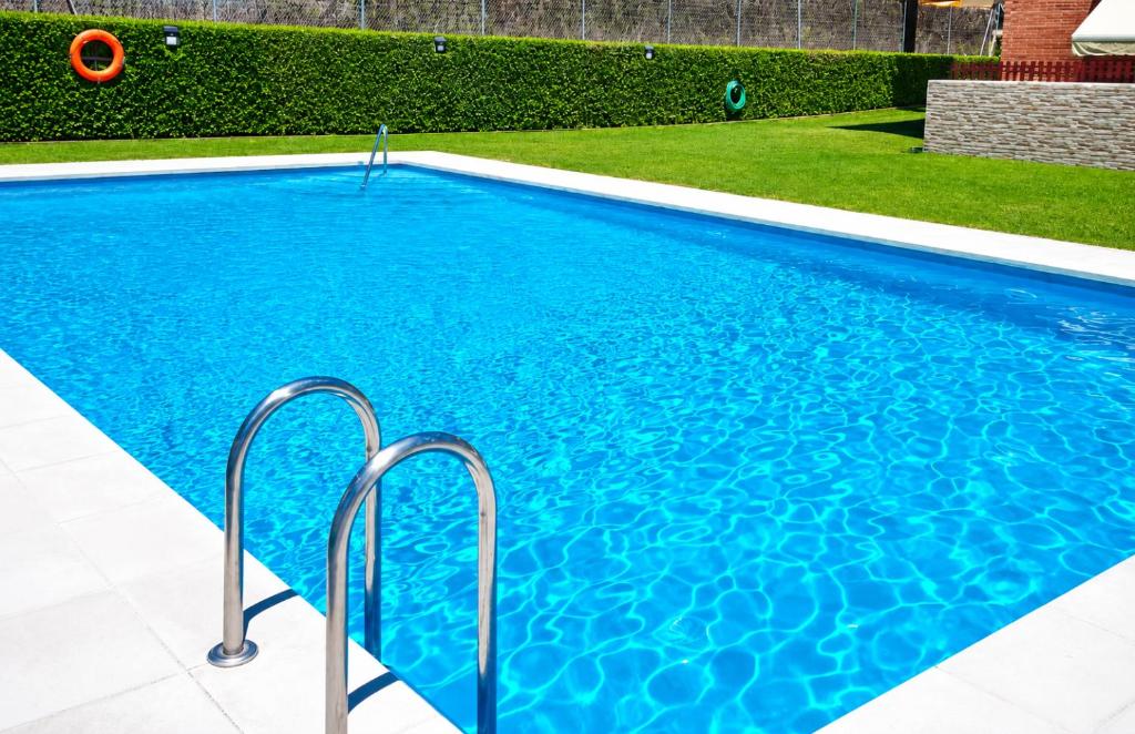 a swimming pool with blue water in a yard at Fenals Calm - con piscina in Lloret de Mar