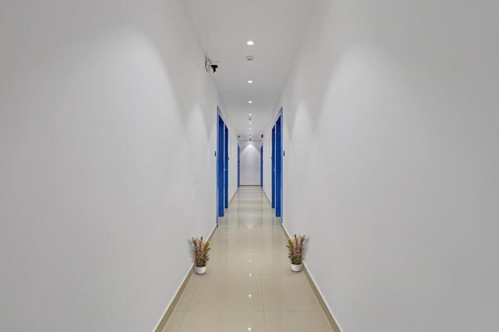 a hallway of a white building with two potted plants at Collection O Leo Palace in Surat