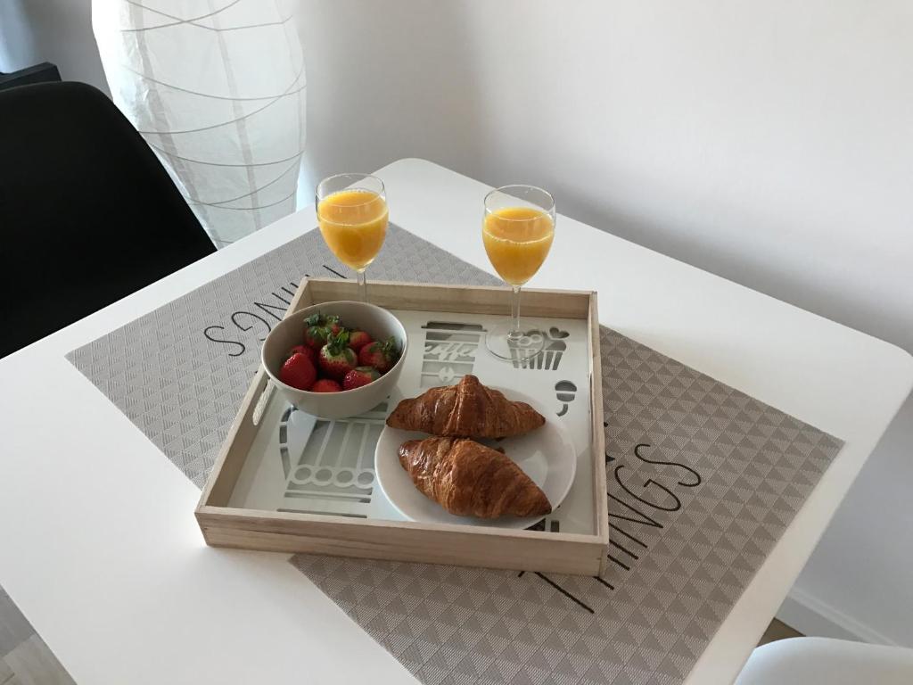una bandeja con un plato de comida y dos vasos de zumo de naranja en Apartament MetroMarymont en Varsovia