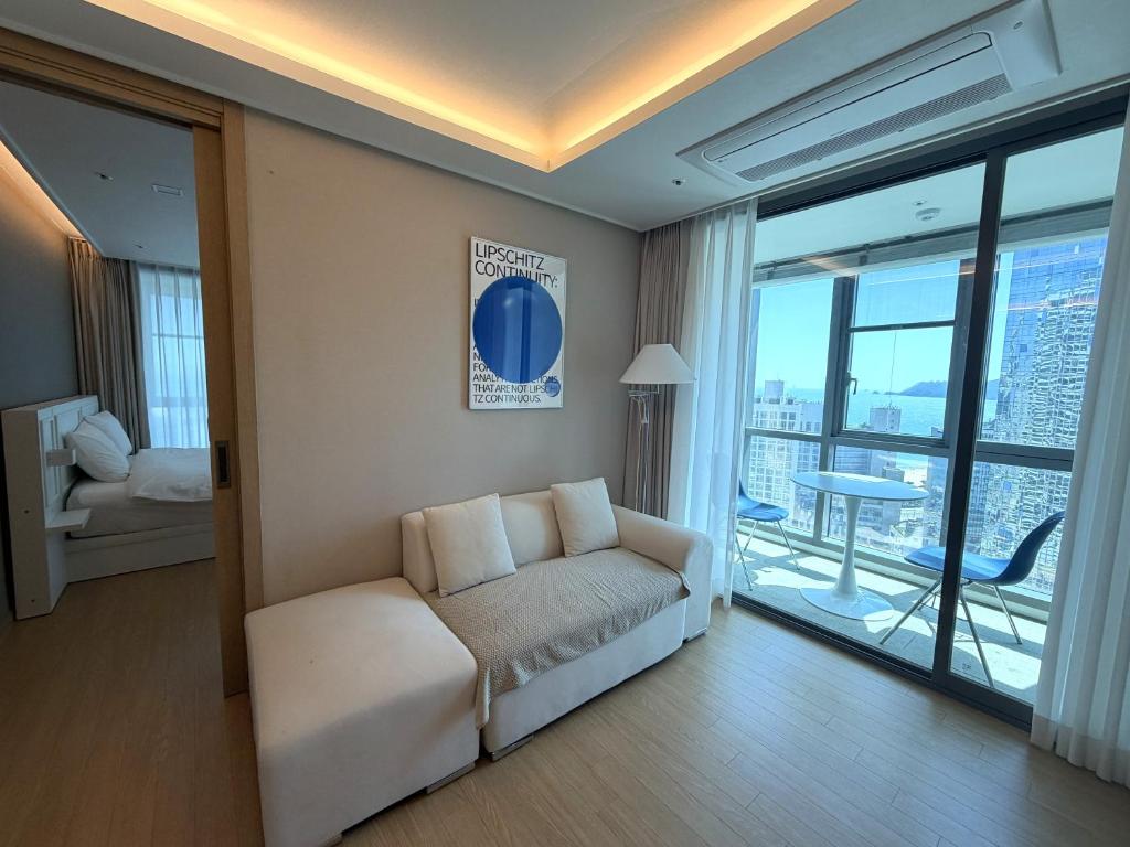 a living room with a couch and a balcony at Bona Together In Haeundae Residence in Busan