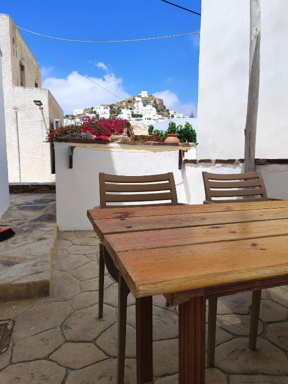 a wooden table with two chairs and a building at Four Seasons Rooms & Apartments in Ios Chora