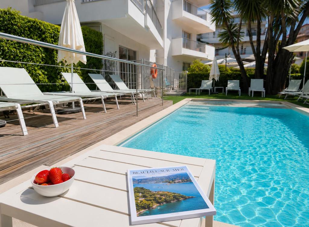 a book sitting on a table next to a swimming pool at Résidence Carlton - Rénovée avec Piscine in Beaulieu-sur-Mer