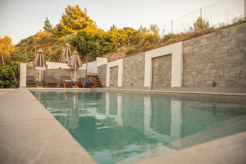ein Schwimmbecken mit Sonnenschirmen neben einer Mauer in der Unterkunft Villa Divina in Kremasti