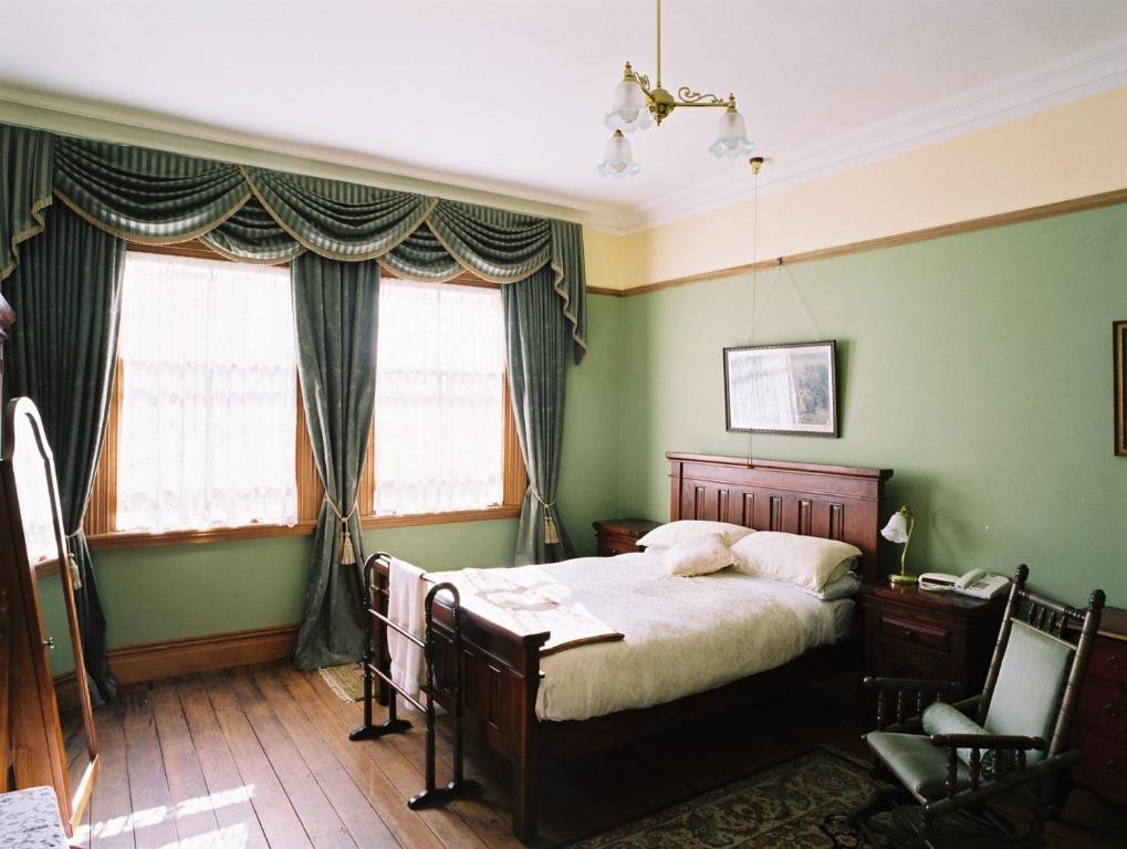 a bedroom with a bed with green walls and windows at Braemar On Parliament St in Auckland