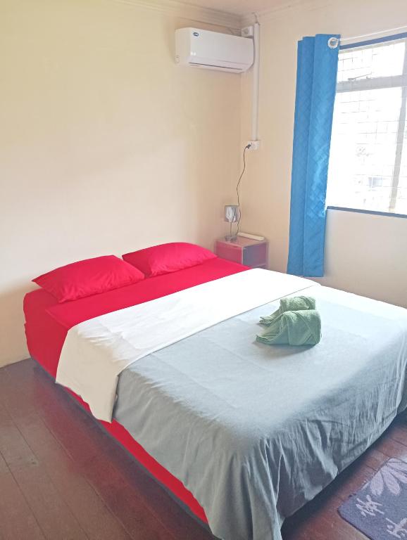 a bedroom with a large bed with red and white sheets at Mishra Residence in Suva