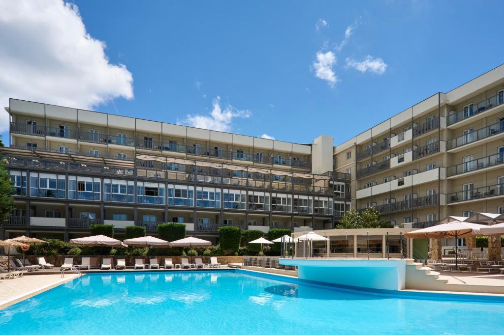 a hotel with a swimming pool in front of a building at Ariti Grand Hotel in Corfu