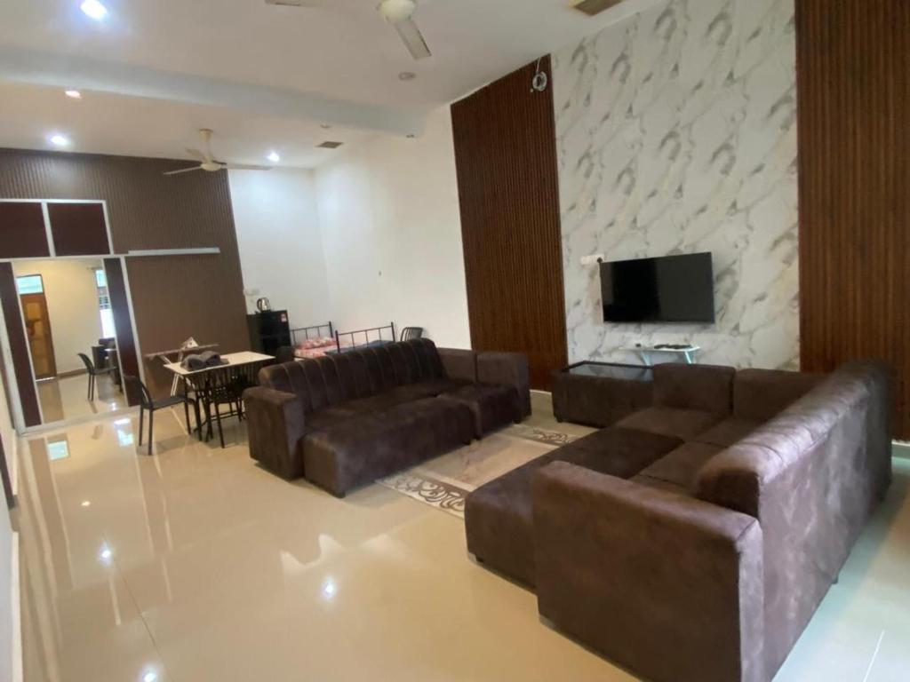 a living room with a couch and a flat screen tv at Legacy Yumai in Kuala Rompin