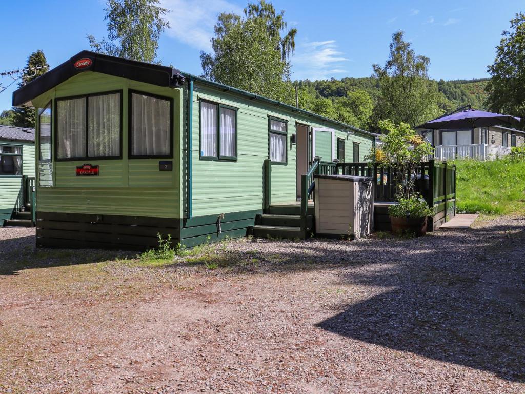 a green tiny house sitting on a gravel lot at Maggie's Place in Dunkeld