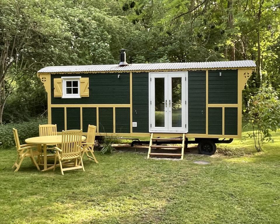 a green tiny house with a table and chairs at The Shepherds Hut in Wallingford