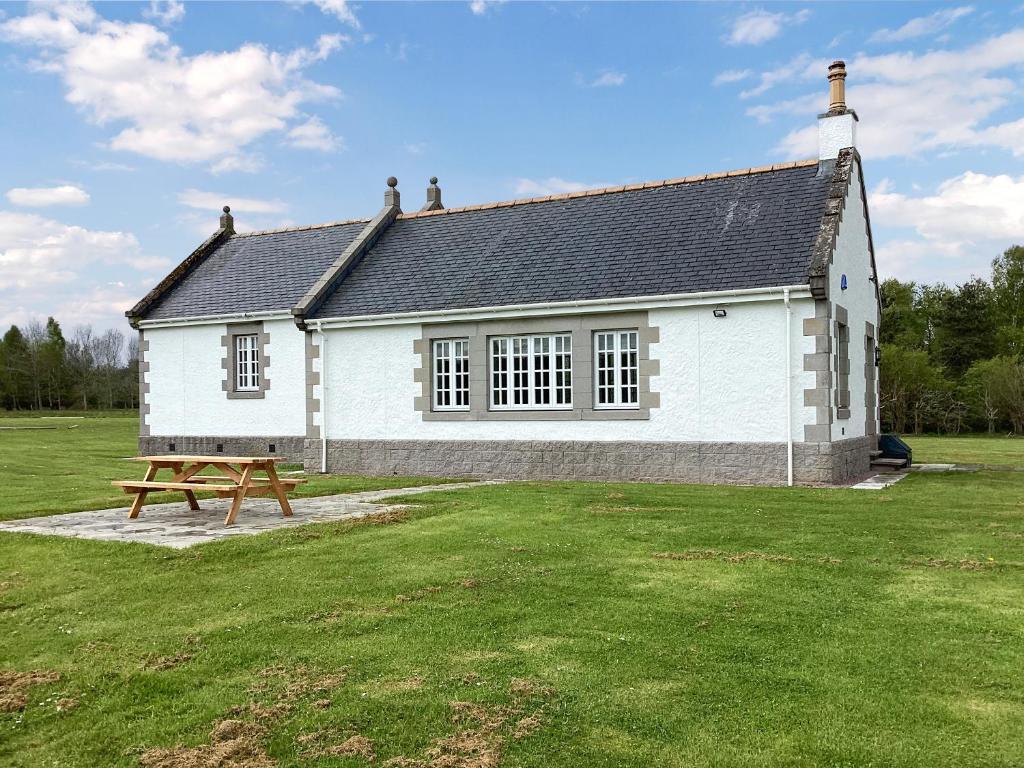 a white house with a picnic table in front of it at The Studio Cottage in Knock