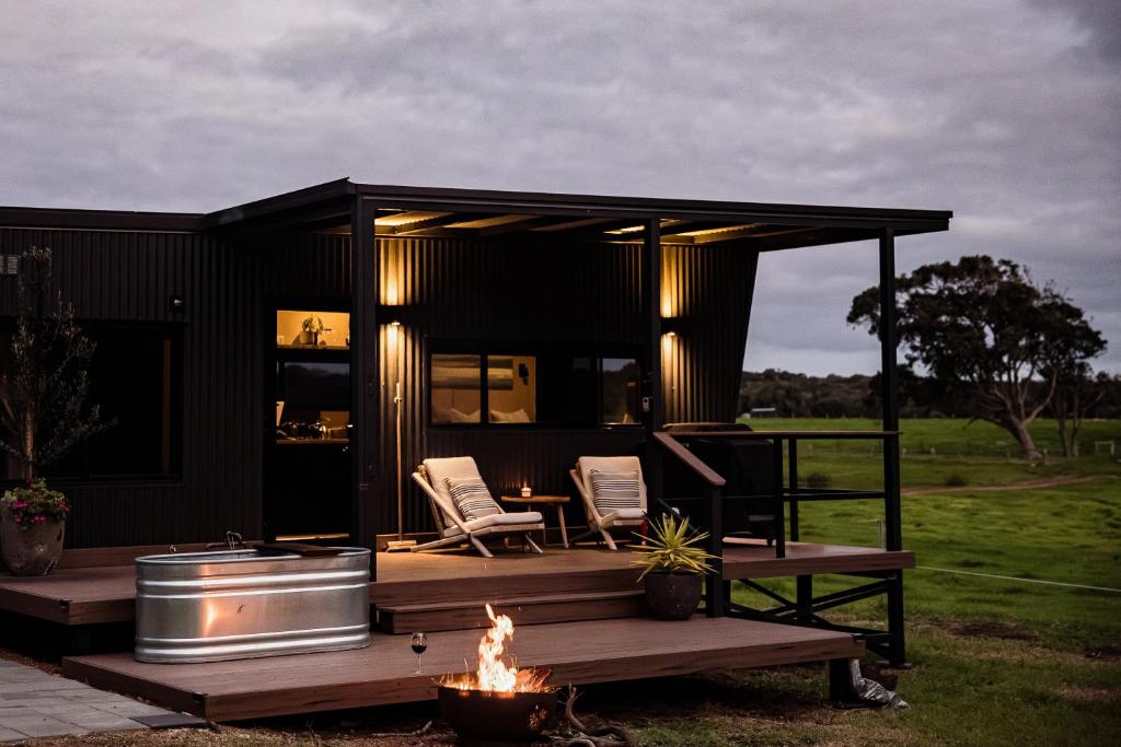 a black house with two chairs and a fire at Heyscape Yallingup in Yallingup