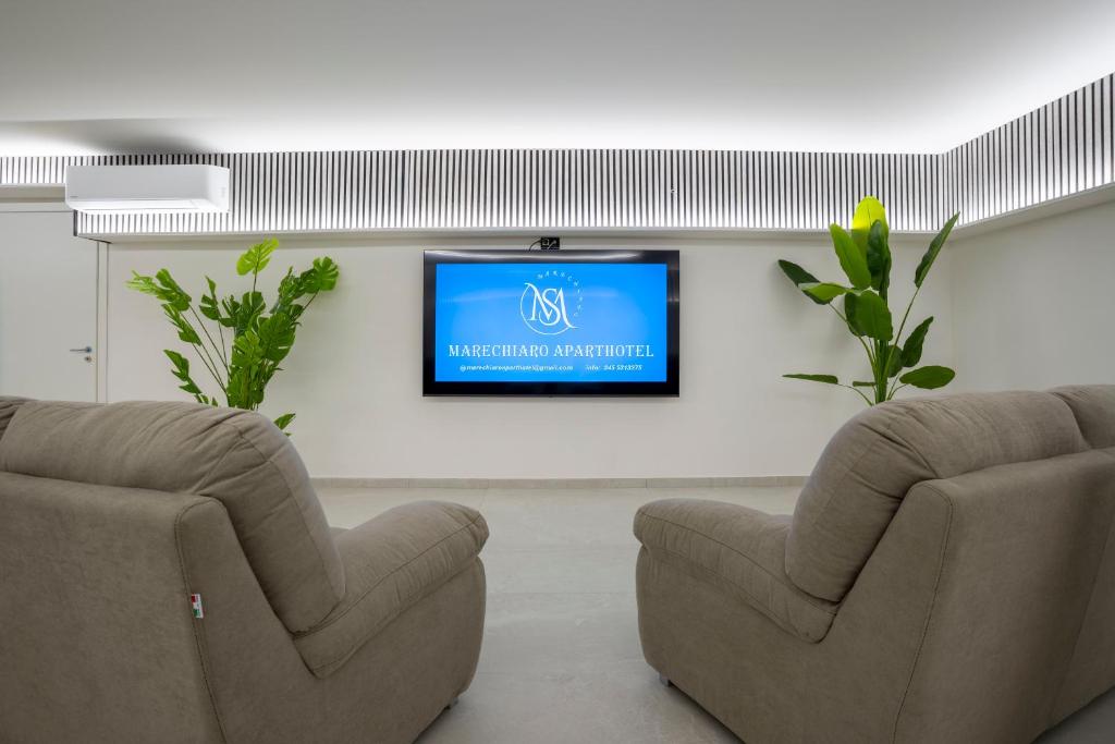 a living room with two chairs and a flat screen tv at Marechiaro Aparthotel in Marina di Camerota