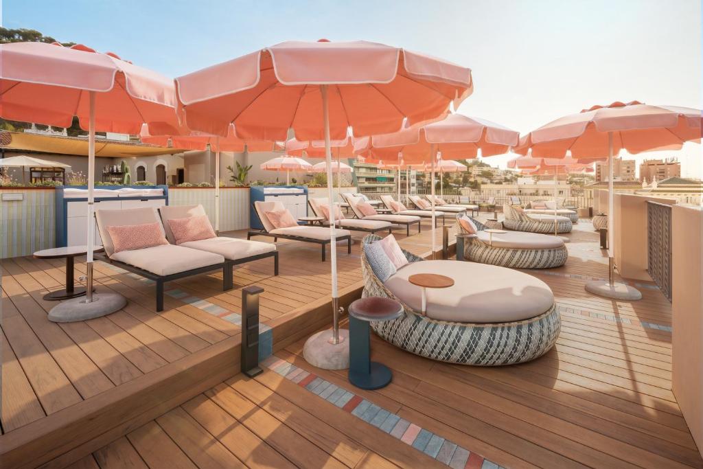 a deck with tables and chairs and umbrellas at Áurea Palacio de la Tinta by Eurostars Hotel Company in Málaga