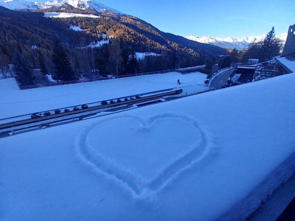a heart drawn in the snow in front of a mountain at Petit Flocon in Pila
