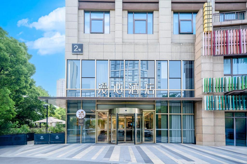 a large building with glass doors and windows at Manxin Hotel Suzhou Jinfeng Road in Suzhou