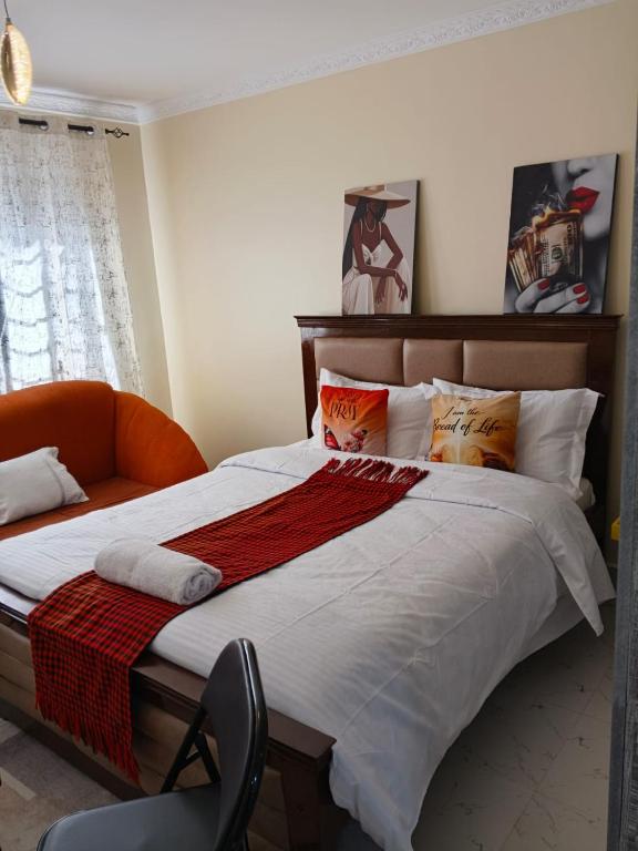a bedroom with a large bed with an orange chair at BnB Studio Oasis Homes Machakos in Machakos