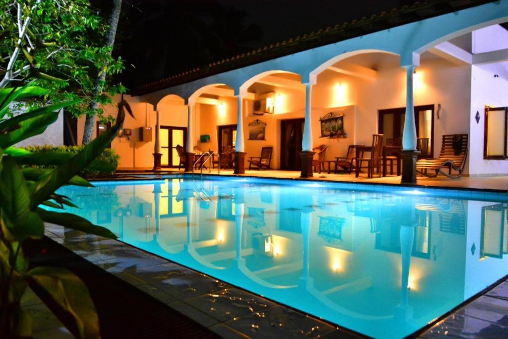 a large swimming pool with lights in a house at Lucas Hotel in Kosgoda