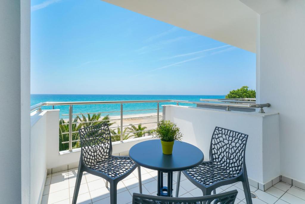 a balcony with a table and chairs and the beach at OzioMari Suites in Limenaria