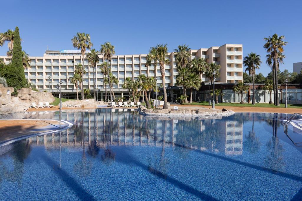 a large swimming pool with a hotel in the background at RVHotels Ametlla Mar in L'Ametlla de Mar