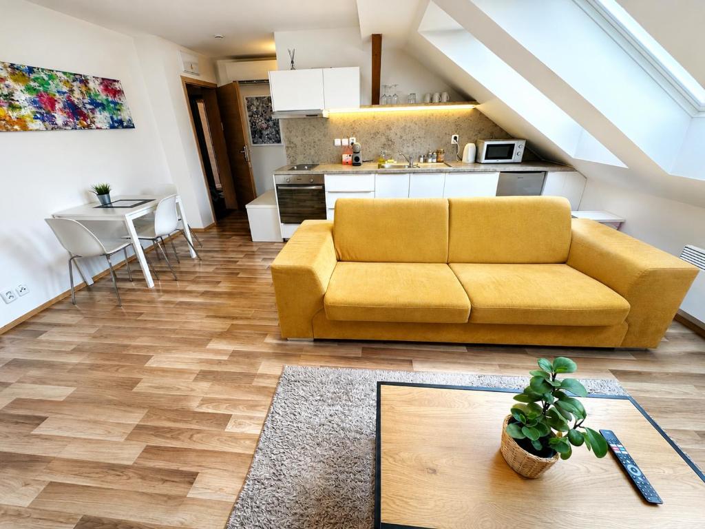 a living room with a yellow couch and a kitchen at Apartmány Skryjova in Brno
