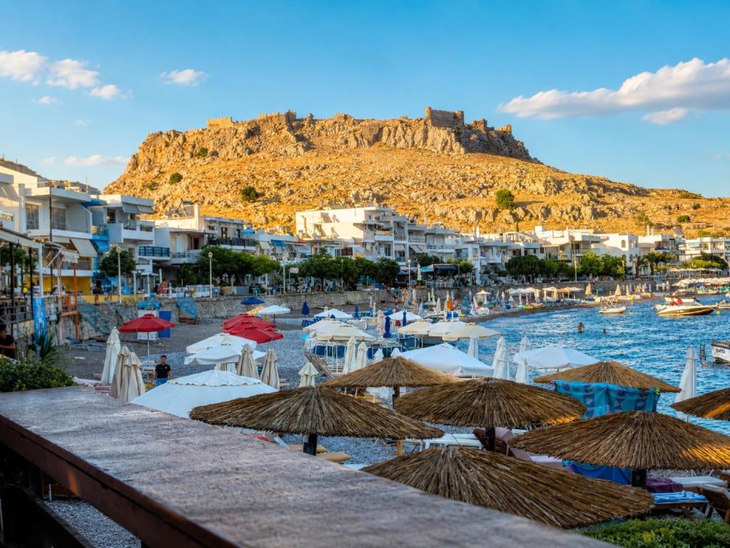 a view of a beach with umbrellas and buildings at Oikos Apartments in Haraki