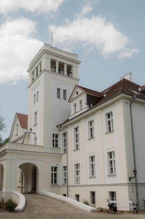 a white building with a tower on top of it at Pałac Przybyszewo in Przybyszewo