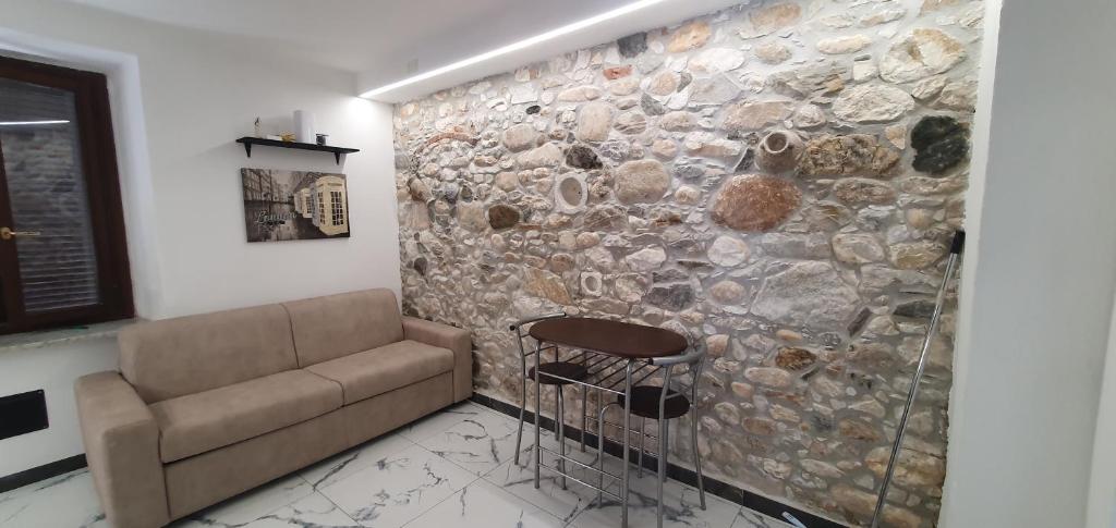 a living room with a couch and a stone wall at Maréa suite con giardino in Marina di Carrara