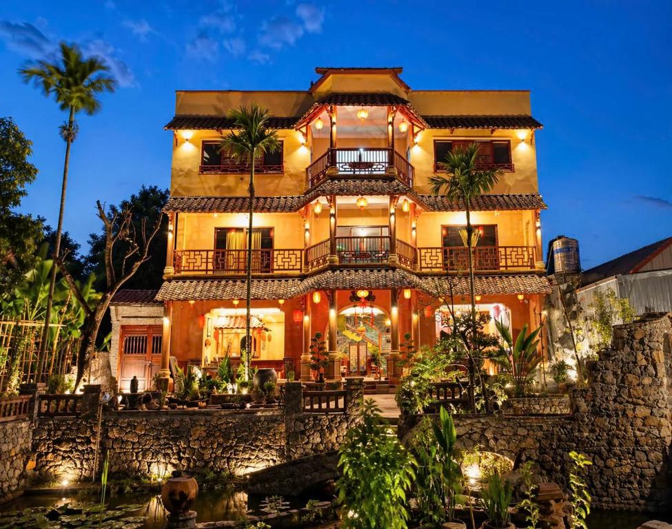 a large building with palm trees in front of it at Y Van Cac Homestay Ninh Binh Art Heritage Rice Field in Ninh Binh