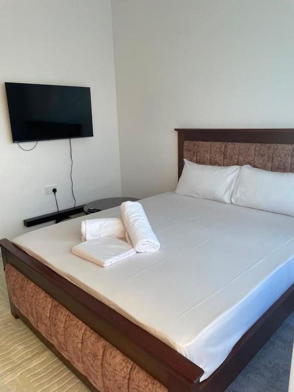 a bed with two pillows and a tv on the wall at royalnest bnb in Mombasa