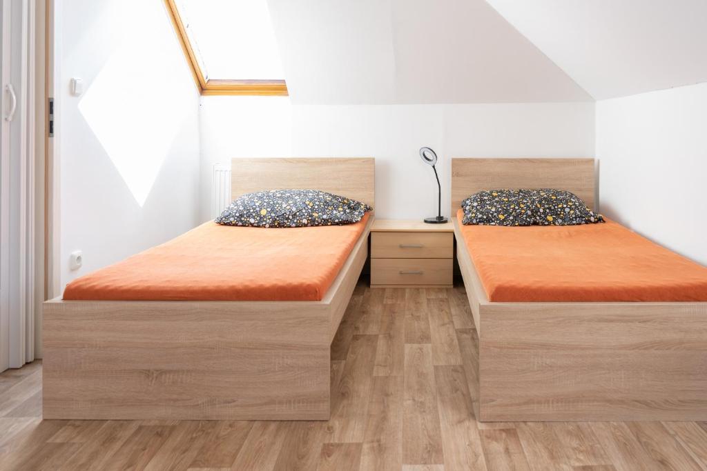 two beds in a small room with wooden floors at Soukromý byt v centru Velkého Meziříčí in Žďár nad Sázavou
