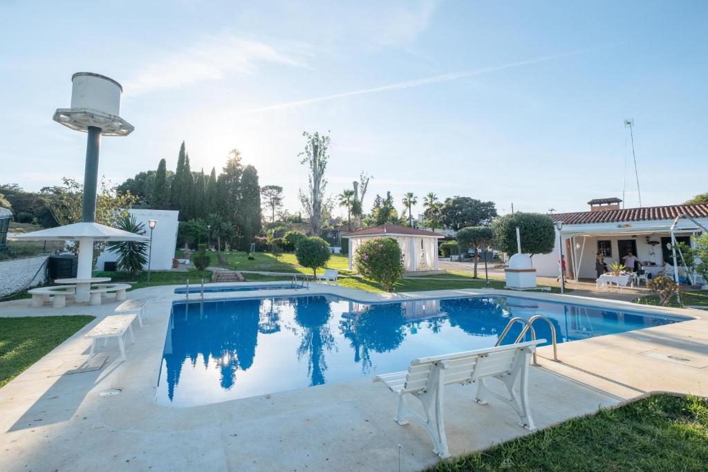 a swimming pool with two white chairs in a yard at Chalet las Pajanosas in Guillena