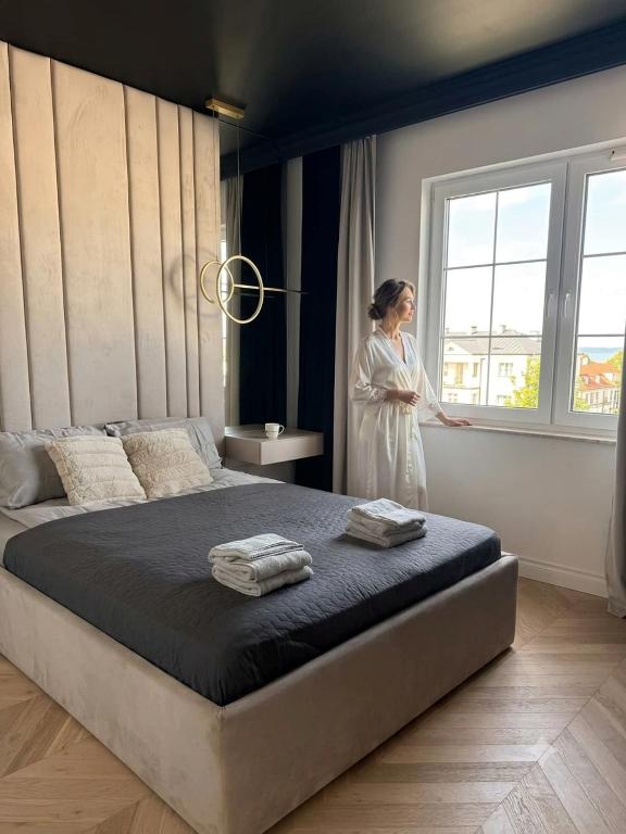 a woman standing next to a bed in a bedroom at Tesoro Dolce Vita Apartment in Pogórze